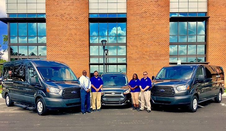 team in front of the vans and busses