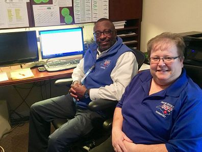 two members of CST team at desk smiling